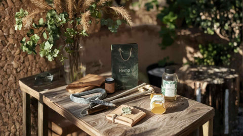 Die besten Geschenkideen für Cannabisliebhaber: Geschenke auf einem Tisch im Freien, mit Hanfprodukten.