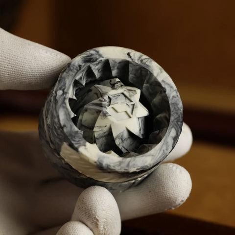 Black Marble Hash Grinder V3 being held, showcasing its ergonomic design and intricate mechanics.